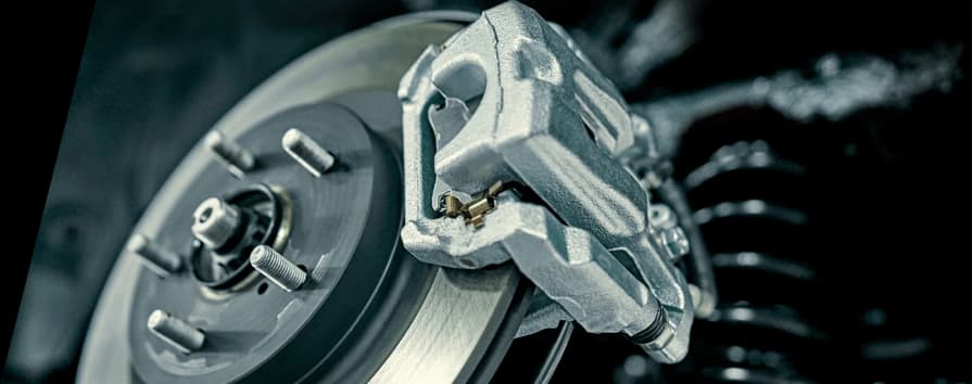 Caliper de freno plateado montado en disco de freno mostrando instalación profesional y componentes de rendimiento
