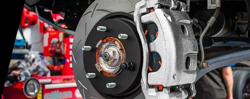 Primer plano de sistema de freno de alto rendimiento mostrando disco ranurado DBA instalado en vehículo con pinza plateada y buje visible