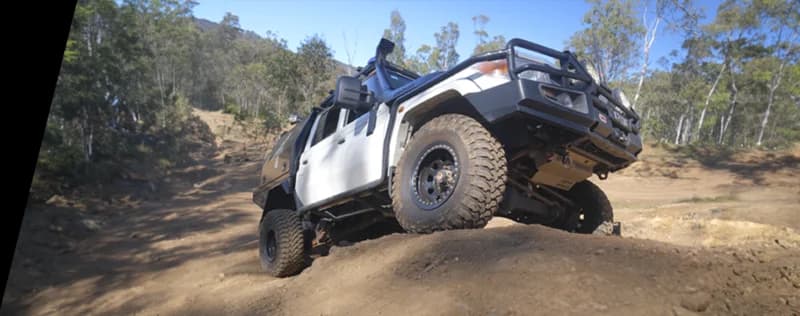 Vehículo 4WD blanco posicionado en pendiente arenosa empinada en terreno monte australiano demostrando capacidad off-road