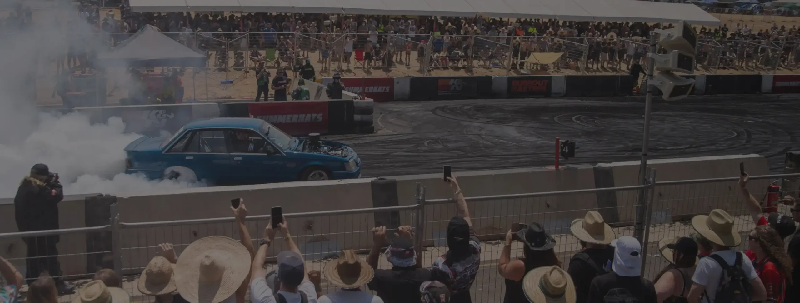 Rendimiento de frenos DBA demostrado en carreras de motor con espectadores viendo coche realizando burnout en circuito