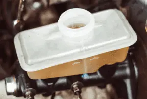 Depósito de líquido de freno correctamente llenado mostrando nivel adecuado en marca máxima tras purga completa del sistema de frenos Depósito de líquido de freno de plástico translúcido mostrando nivel de líquido en línea máxima de llenado tras completar procedimiento de purga