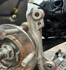 Paso 4B: Identificando puntos de contacto en el buje original que requieren eliminación para ajuste adecuado de la pinza DBA Buje original con área de contacto visible marcada para modificación para asegurar espacio adecuado para la instalación de la pinza DBA