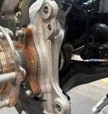 Paso 4A: Inspeccionando el buje original para identificar puntos de contacto con la pinza DBA después de la modificación de la placa Primer plano del buje original y placa de respaldo modificada mostrando posibles puntos de contacto con la pinza DBA durante la instalación